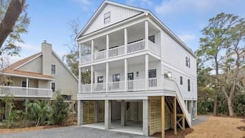 A two-story house with a balcony on the upper floor, a covered front porch, and a staircase leading to the entrance.