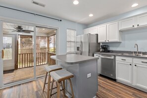 Una cocina moderna con una isla grande, electrodomésticos de acero inoxidable y un  puerta corrediza de vidrio que da a una terraza.