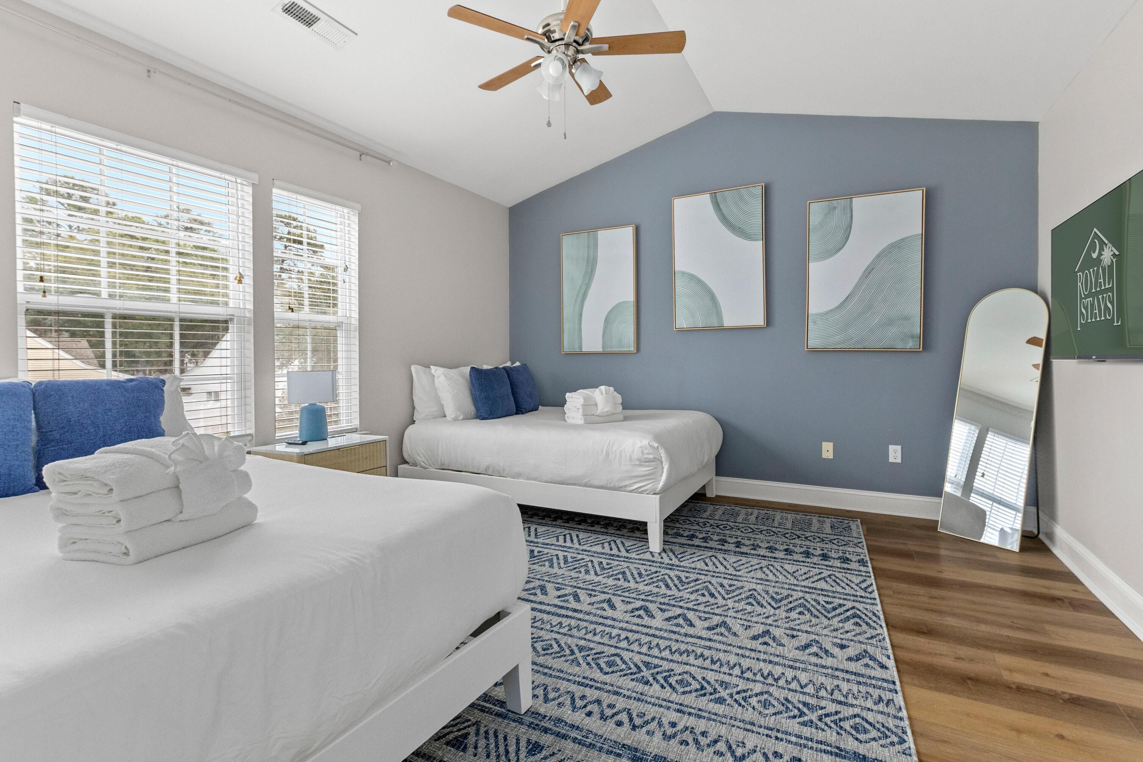 A bedroom with a bed, a nightstand, a mirror, and artwork on the wall.