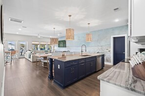 A modern kitchen with a central island, dark cabinetry, and pendant lighting. - Between Tides-pool- Walk to Beach (Murrells Inlet)
