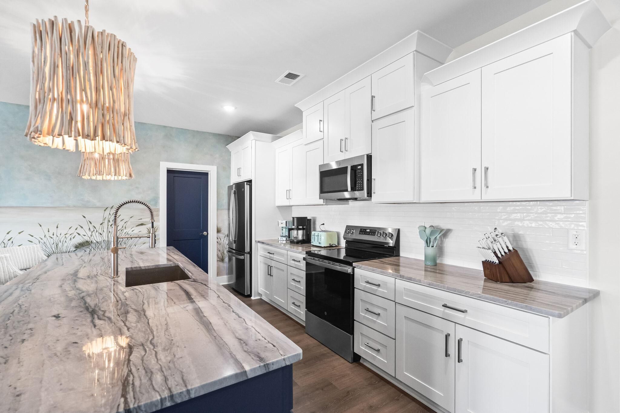 A modern kitchen with white cabinets, stainless steel appliances, and a marble island.