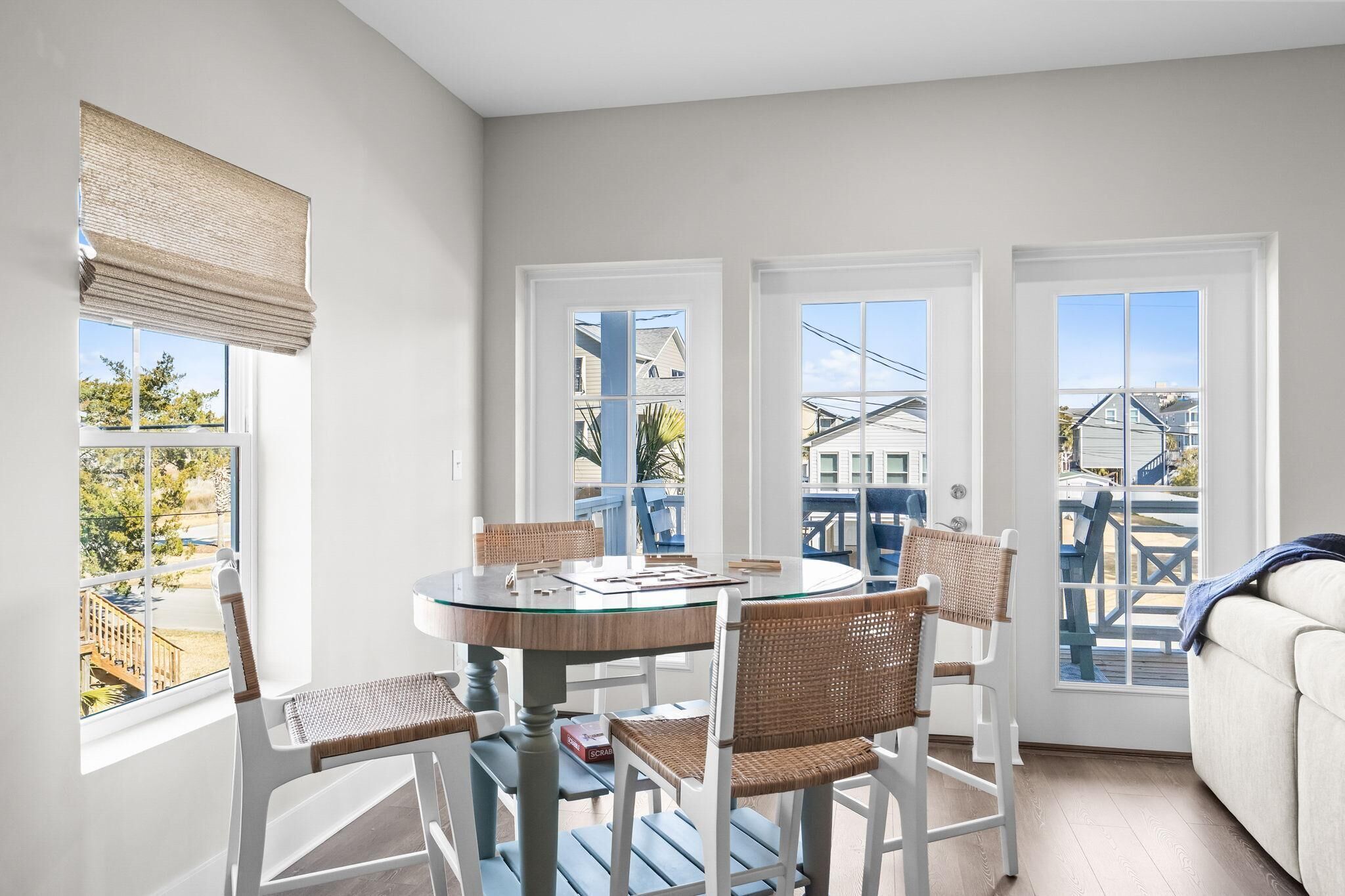 A bright room with a round glass table, white chairs, and a view of the outside.