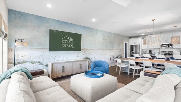 Una sala moderna con sofá, reposapiés y un comedor con sillas y una mesa.