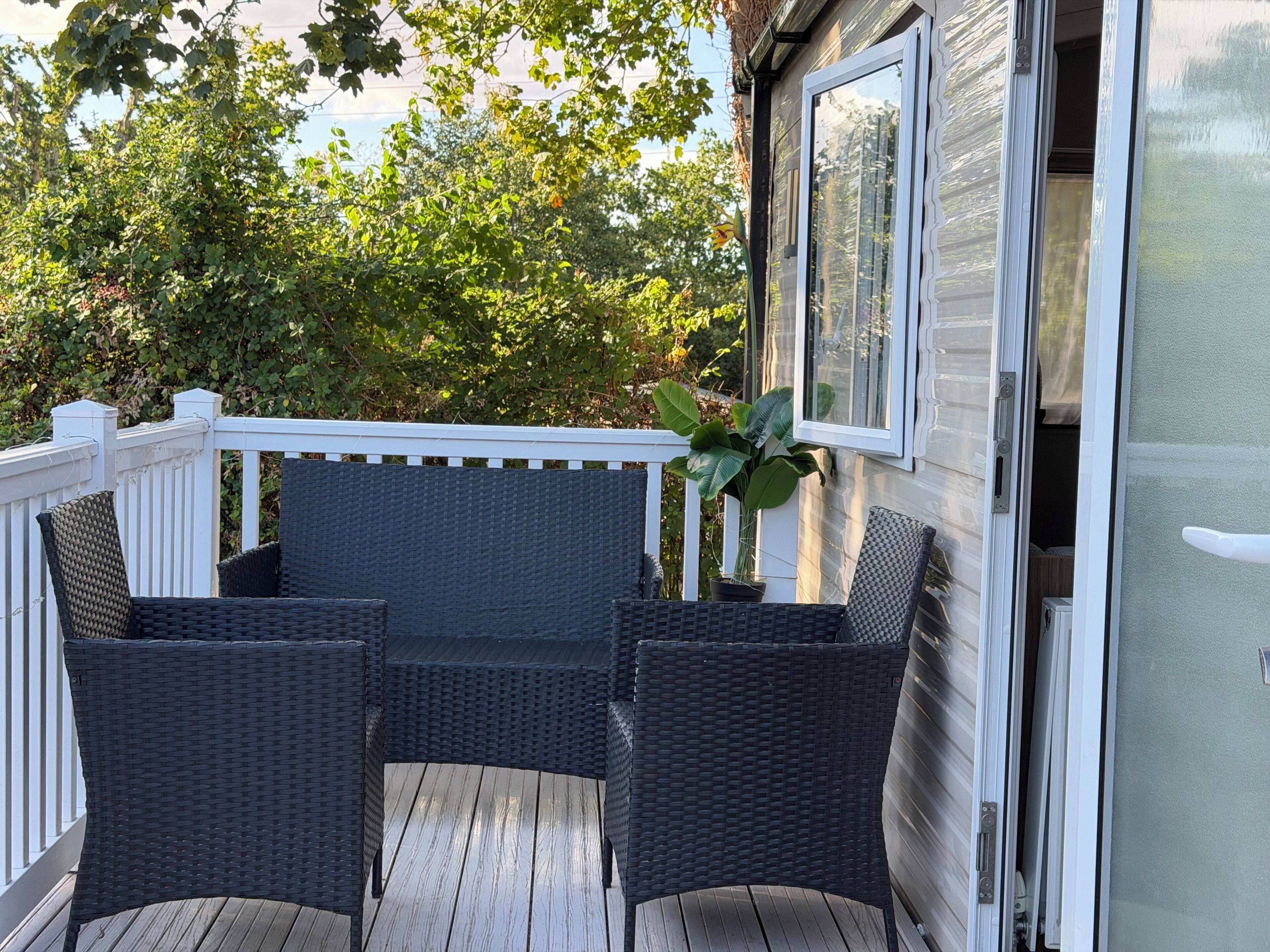 A covered outdoor seating area with wicker furniture and a potted plant.