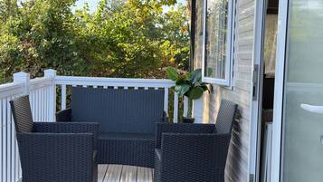 A covered outdoor seating area with wicker furniture and a potted plant.