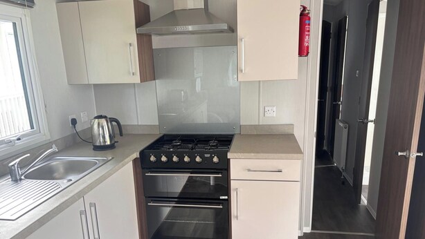 Una cocina compacta con estufa a gas, horno y un lavamanos.