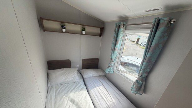 A small, single-bed room with a window, a shelf with potted plants, and a curtain. - Cabin Sleeps 8 - Free Parking, Patio, Pool (Poole)
