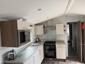 A compact kitchen with a microwave, toaster, sink, stove, and oven. - Cabin Sleeps 8 - Free Parking, Patio, Pool (Poole)