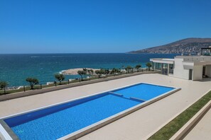 A swimming pool with a view of the sea and a cityscape in the background.