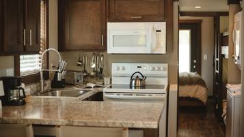 A kitchen with a microwave, stove, sink, and various utensils.