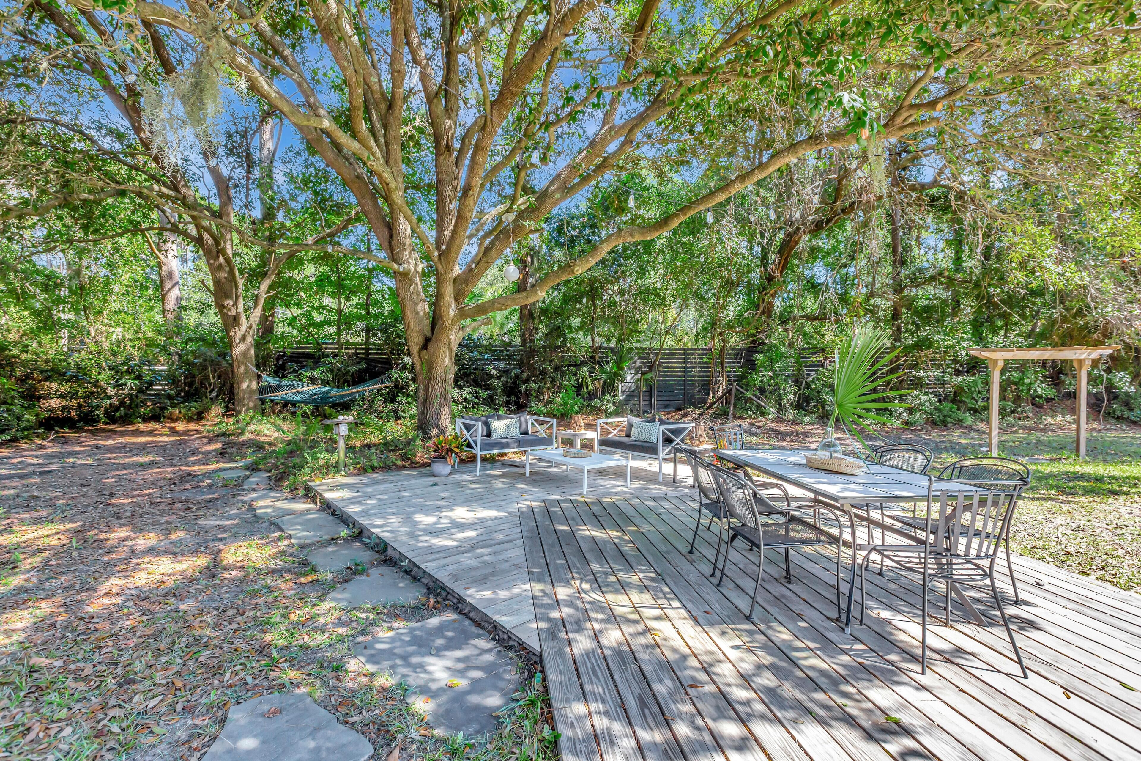 Una terraza con mobiliario exterior, rodeada de árboles y un jardín.