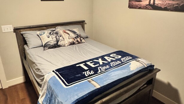 A bedroom with a bed, a ceiling fan, a framed picture, and a wall poster. - Modern Craftsman Home in Houston's Historic 1st Ward/Heights (Houston)