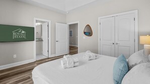 A hotel room with a bed, two doors, a mirror, and a wall-mounted sign. - Pier View-sleeps 10-pets-walk to Beach (Myrtle Beach)