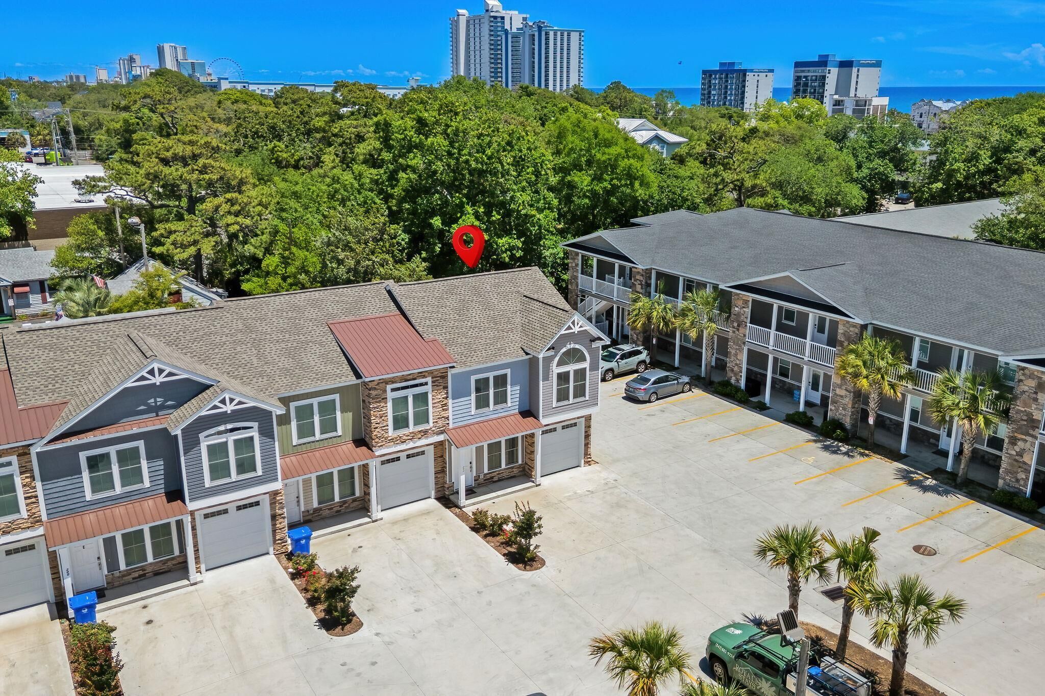 A residential area with houses, a parking lot, and a large building with a red location marker.