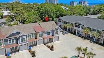 A residential area with houses, a parking lot, and a large building with a red location marker.