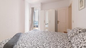 Een slaapkamer met een bed, een kledingkast en een deur naar een andere kamer.