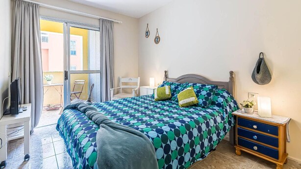 A bedroom with a bed, bedside table, and a chair. - Vacation Apartment 'Alquilaencanarias-el Médano Delfines' with Balcony and Wi-Fi (El Médano)