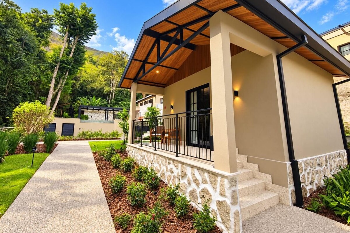 A modern house with a covered porch, stone foundation, and a pathway leading to the entrance.