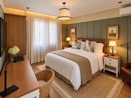 Un dormitorio de hotel moderno con una cama grande, lámparas de noche, un escritorio y una silla.