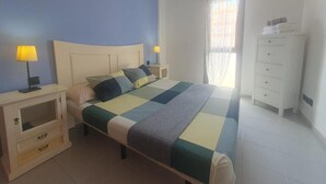 A bedroom with a bed, bedside lamps, a dresser, and a window with curtains. - Vacation Apartment 'Alquilaencanarias Duplex Beach' with Balcony and Wi-Fi (El Médano)