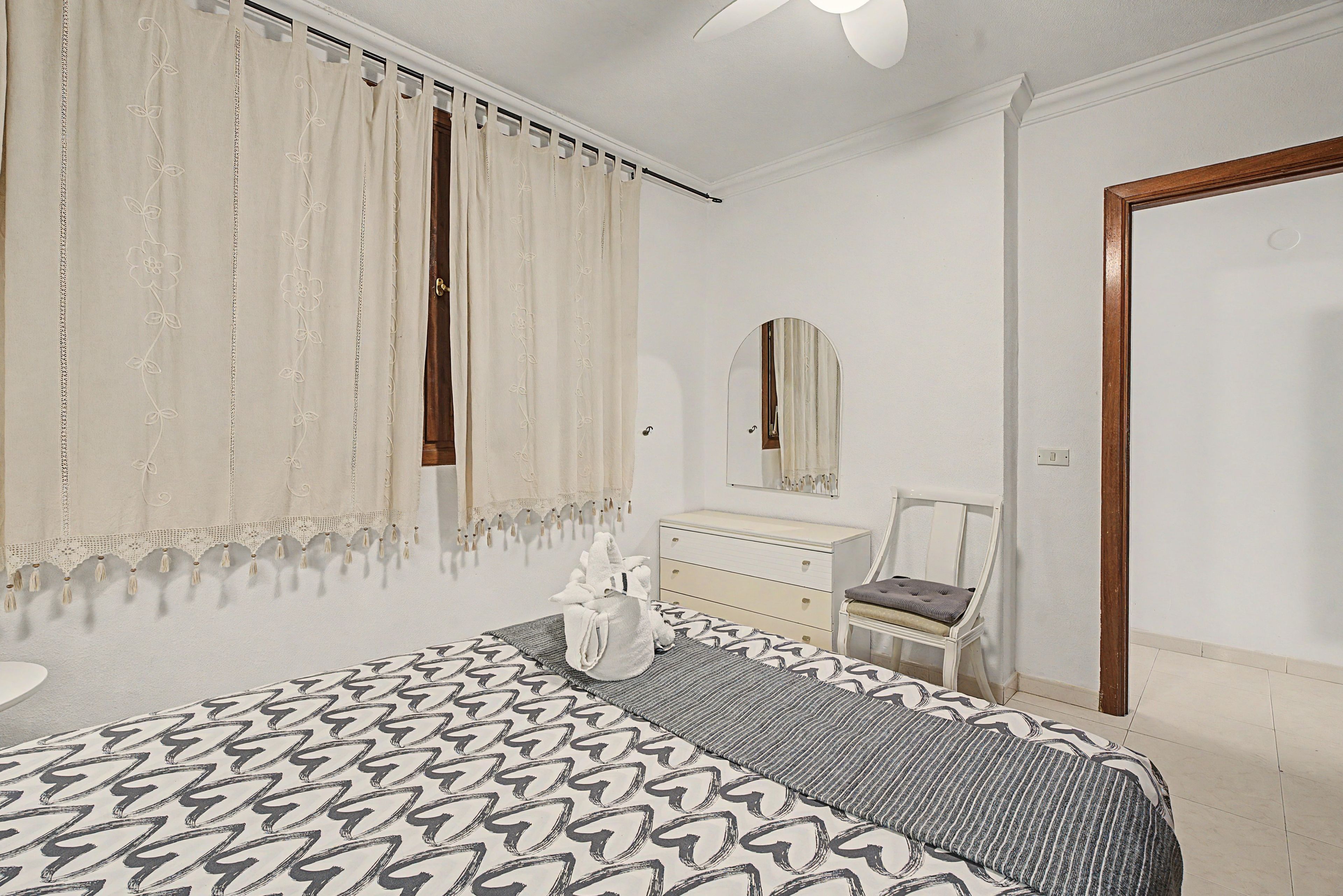 Un dormitorio con cama, cómoda, silla, espejo y puerta.