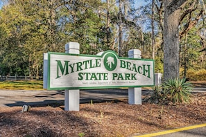 A sign for Myrtle Beach State Park, with a logo and text indicating it is managed by the South Carolina Department of Parks, Recreation & Tourism. - Azure Costa Suite - Beach & Boardwalk (Myrtle Beach)