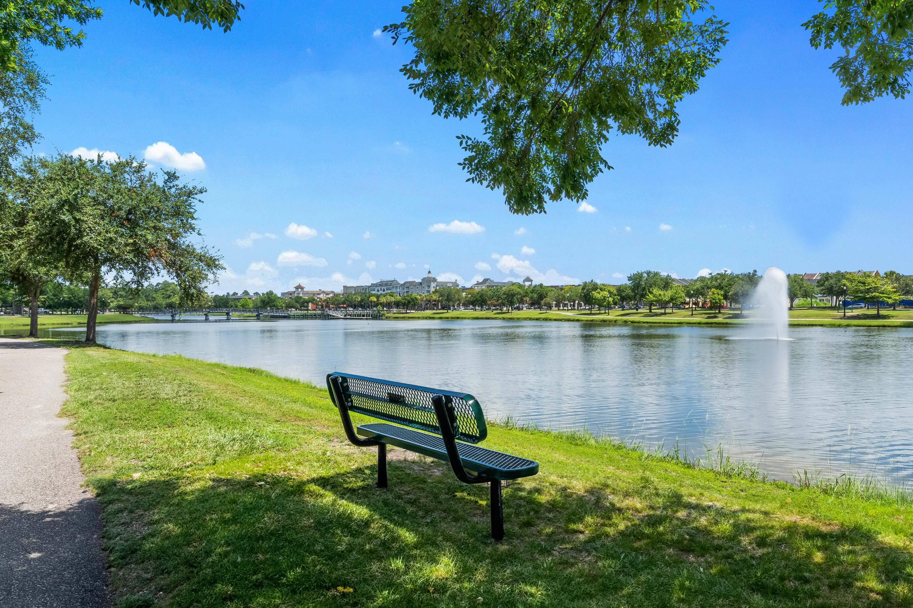 A park with a bench, a lake, and a fountain.