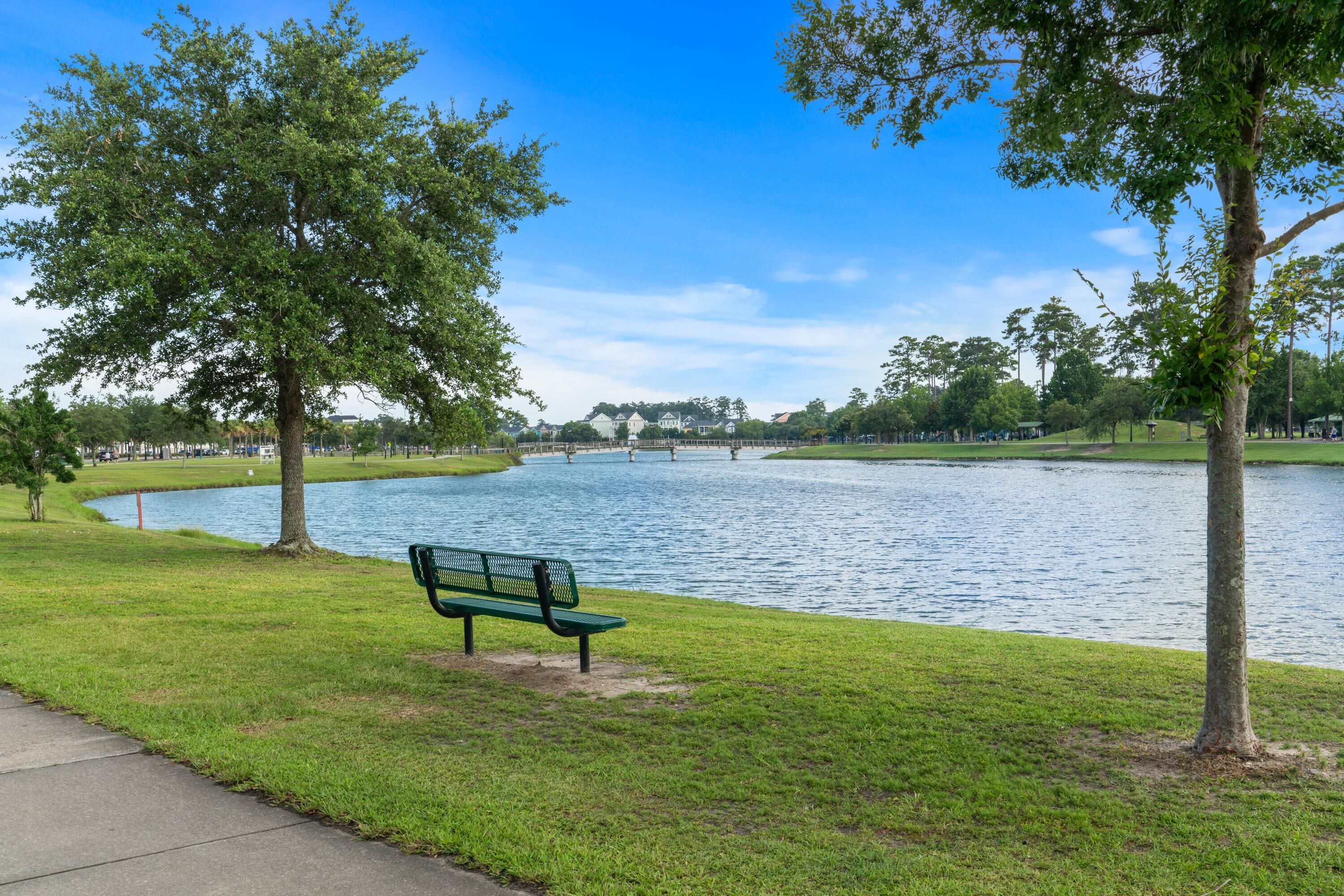Un parque con un banco, un lago y árboles.