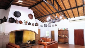 A spacious living room with a fireplace, leather furniture, and a high ceiling with exposed beams.