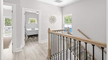 Un interior moderno con una escalera, vistas al exterior y una puerta que da a otra habitación.
