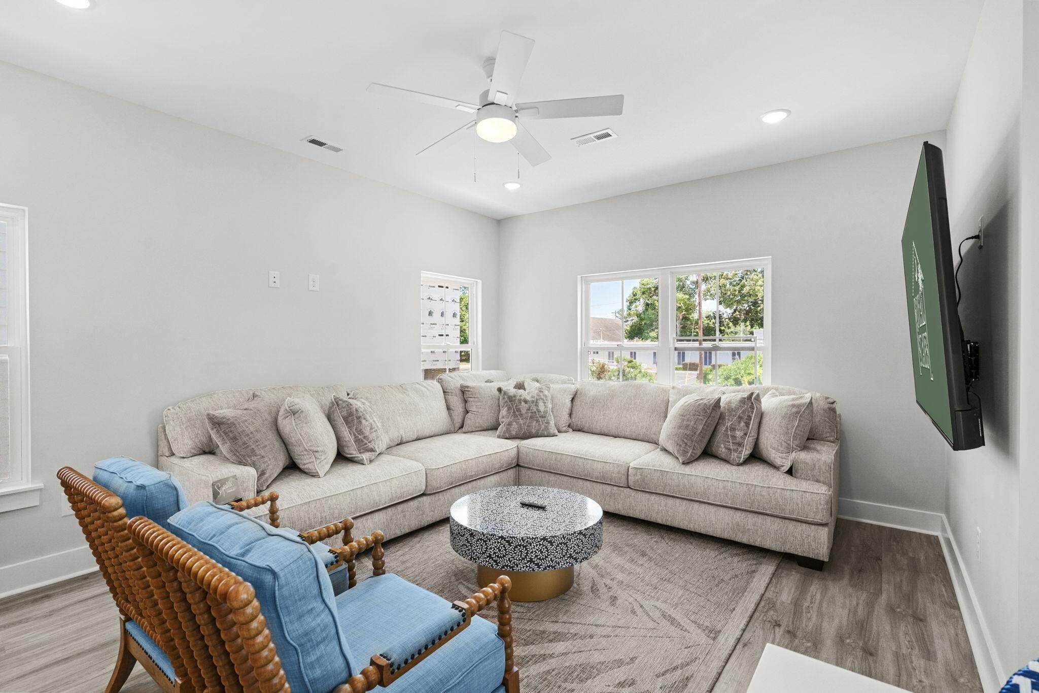 A modern living room with a sectional sofa, a round coffee table, and a ceiling fan.