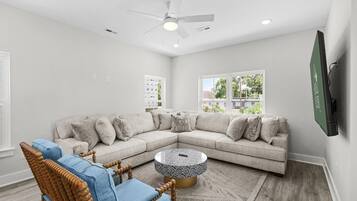 A modern living room with a sectional sofa, a round coffee table, and a ceiling fan.
