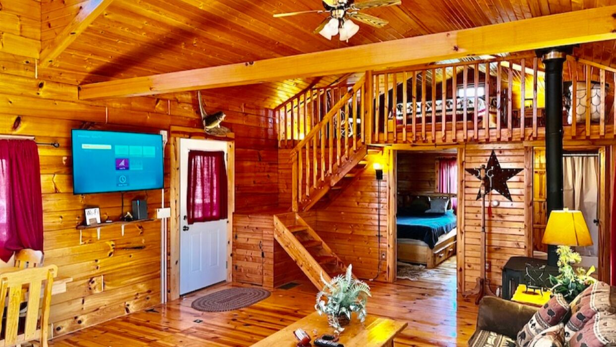 L'intérieur d'un chalet en bois, avec un téléviseur, un escalier et un lit.