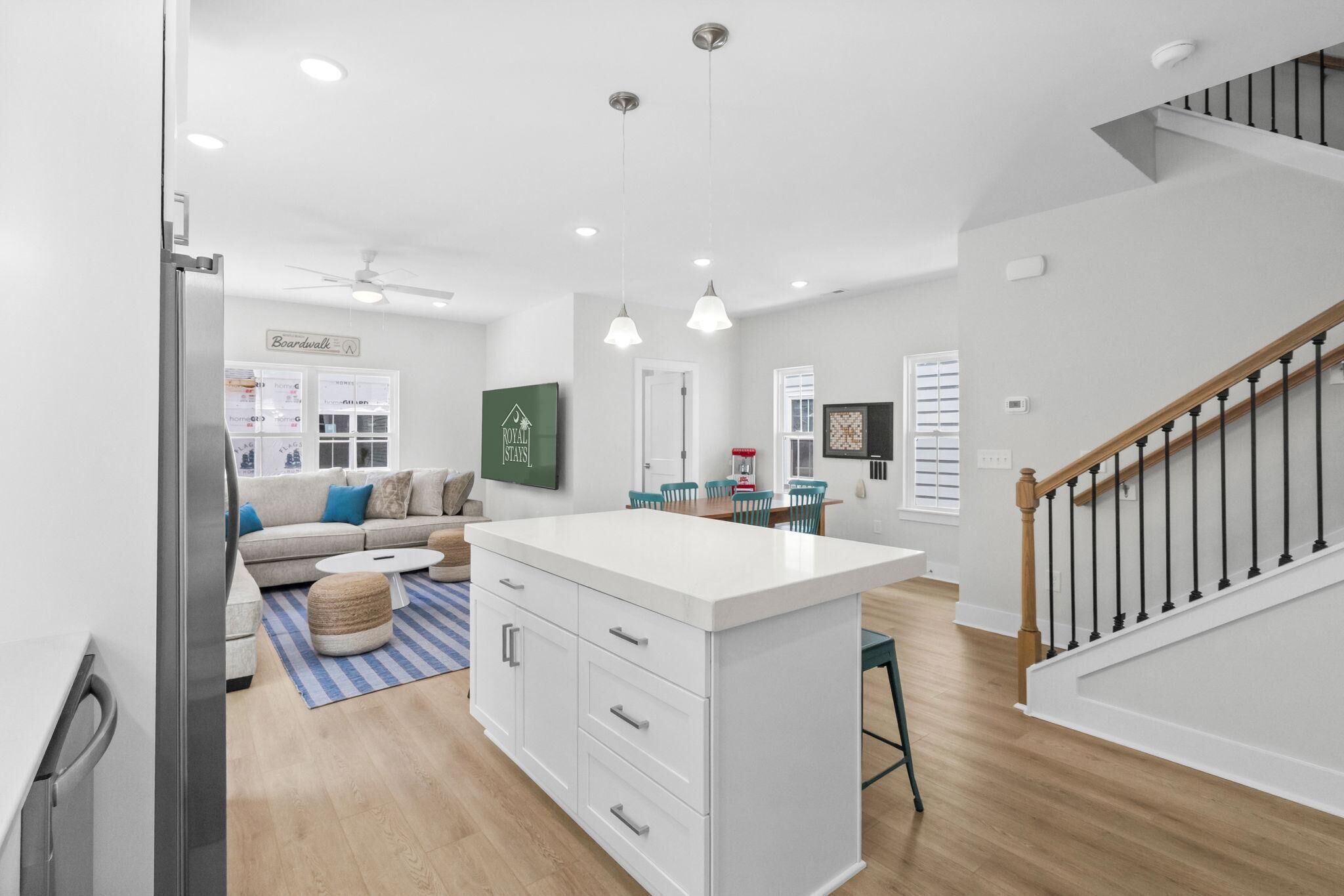 A modern kitchen with white cabinetry, a central island, and pendant lighting.