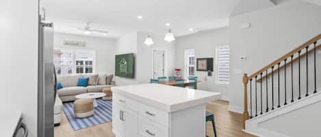 A modern kitchen with white cabinetry, a central island, and pendant lighting.