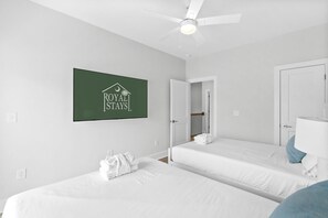 A hotel room with two beds, a ceiling fan, a sign reading 'ROYAL STAYS,' and a bathroom with a mirror and towel. - Boardwalk Bliss 2.5 Blocks to Ocean Pet Friendly (Myrtle Beach)