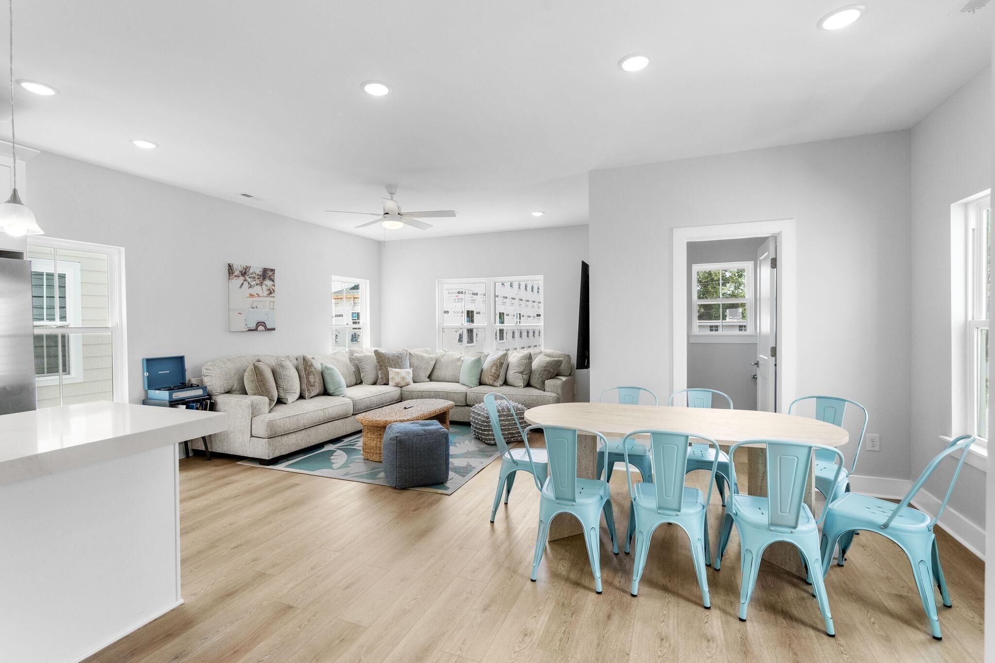 Un salon moderne comprenant un canapé, une table à manger avec des chaises et un coin cuisine avec un réfrigérateur.
