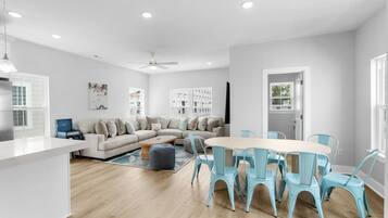 Un salon moderne comprenant un canapé, une table à manger avec des chaises et un coin cuisine avec un réfrigérateur.