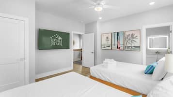 A hotel room with two beds, a ceiling fan, artwork on the wall, and a sign for Royal States.