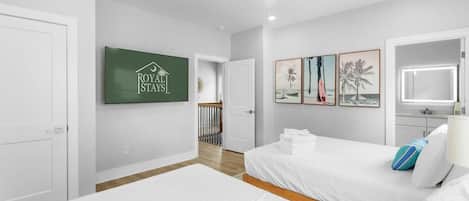 Une chambre d’hôtel avec deux lits, un ventilateur de plafond, des œuvres d’art accrochées au mur et une enseigne indiquant « Royal States ».