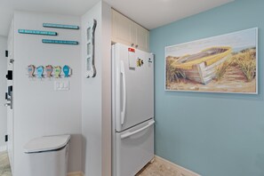 Une cuisine avec un réfrigérateur blanc, une poubelle et un mur orné de panneaux décoratifs en forme de poisson.