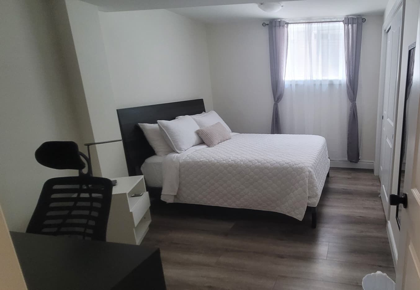 A bedroom with a bed, a desk, and a chair.