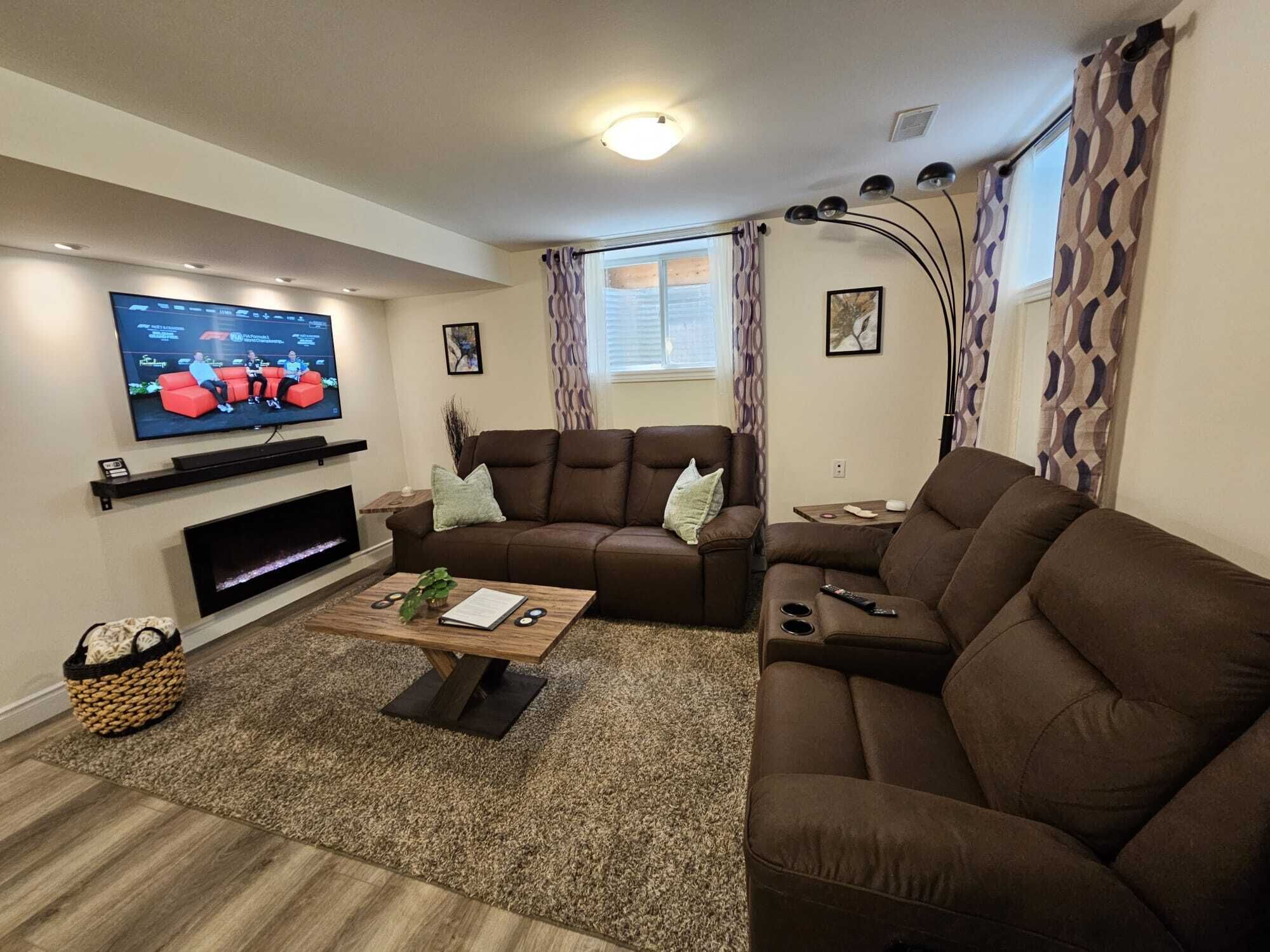A living room with a flat-screen TV, brown leather sofas, a coffee table, and a fireplace.