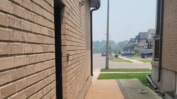 A narrow alleyway with a brick building on one side and a sidewalk on the other. There is a potted plant and a small orange object on the ground.