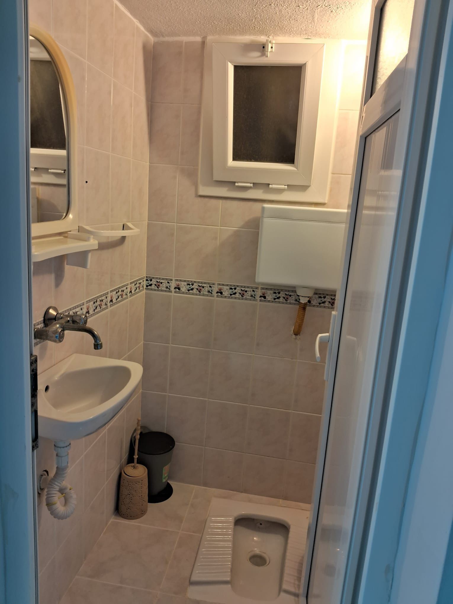 A bathroom with a toilet, sink, and mirror.