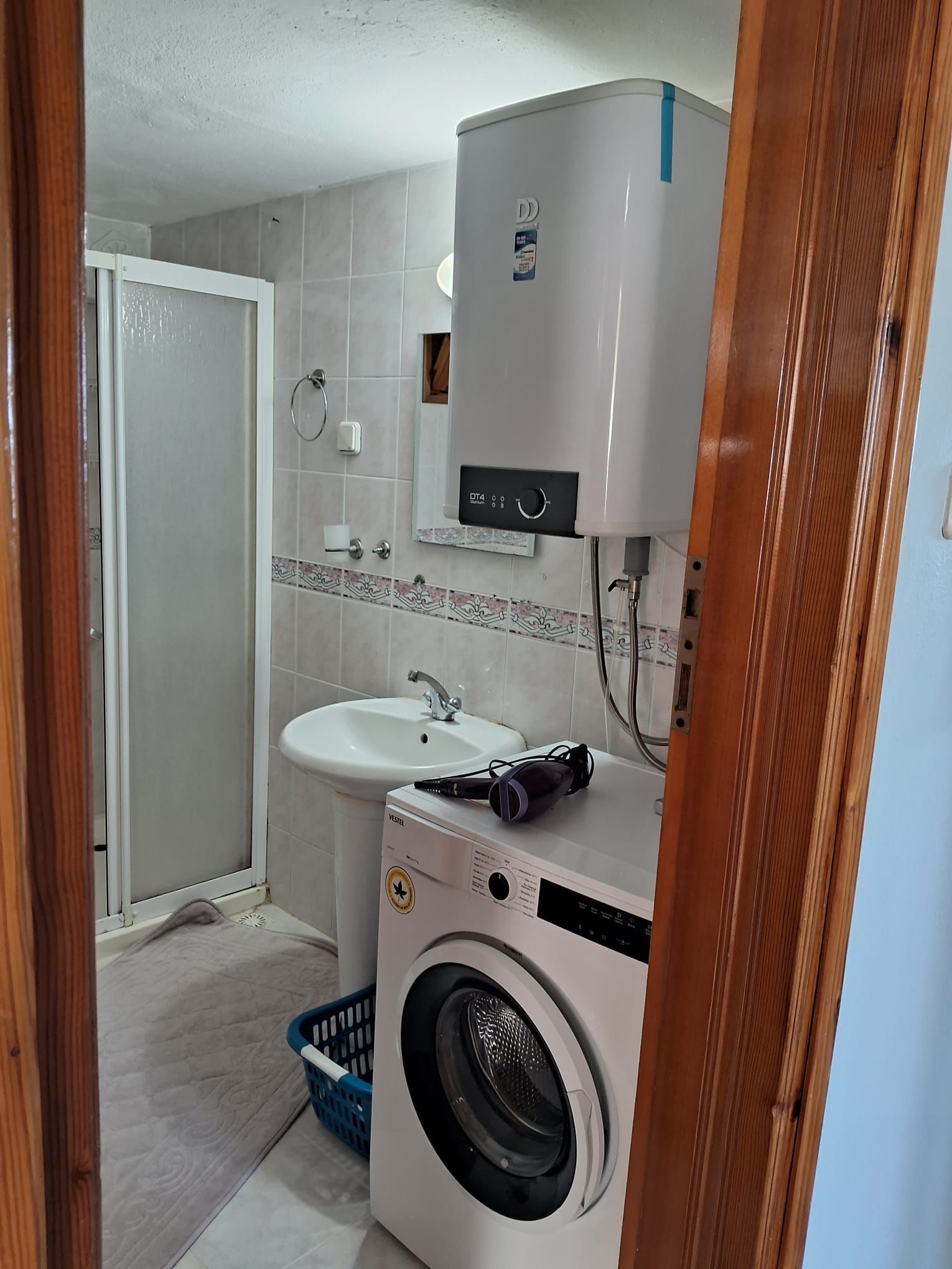 Une petite salle de bain équipée d’un lave-linge, d’un évier et de toilettes.
