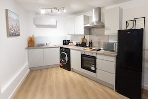 A modern kitchen with a washing machine, oven, microwave, and a refrigerator. - Stylish City-Centre Apartment with Private Balcony (Wolverhampton)