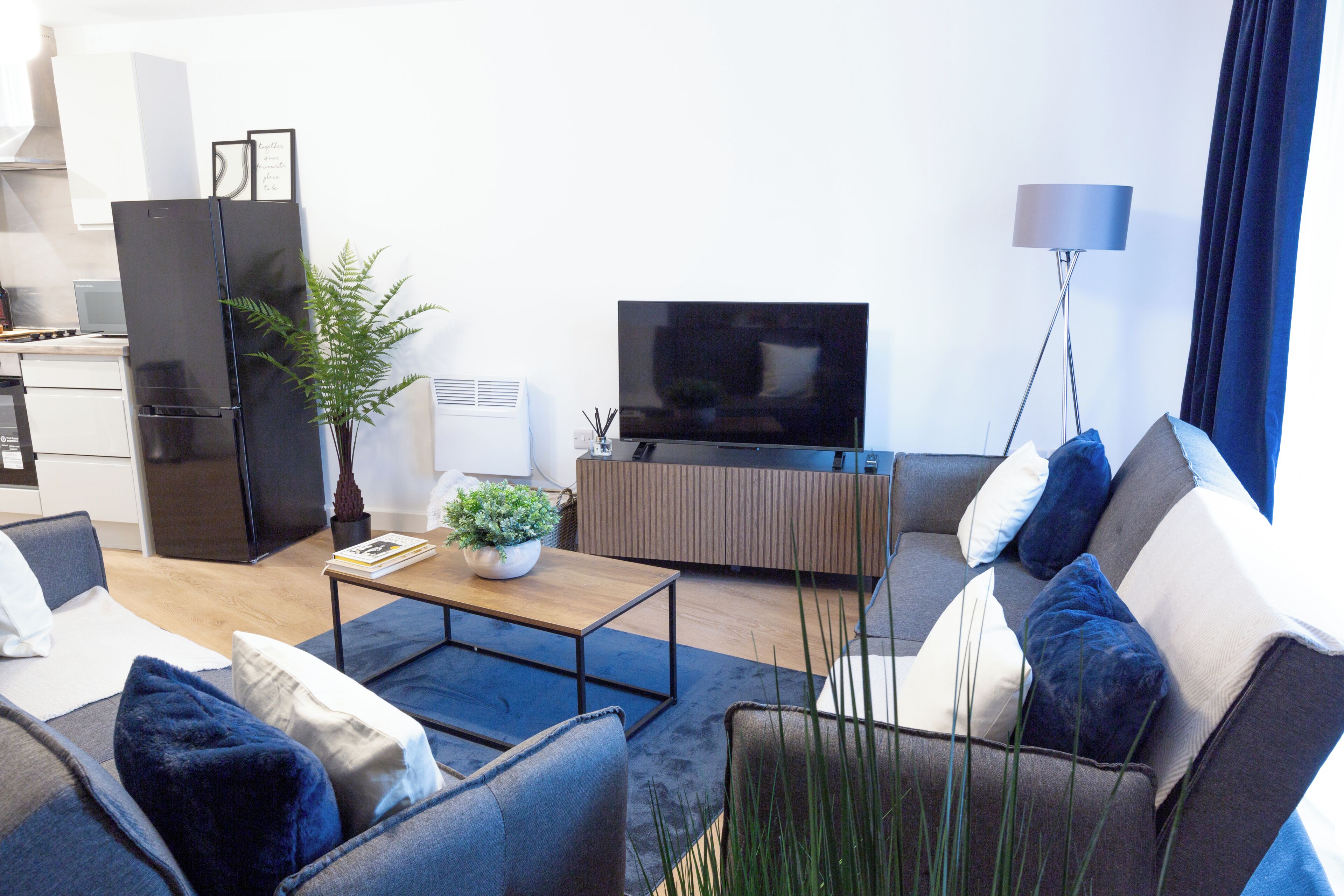 Ein modernes Wohnzimmer mit einer Couch, einem Couchtisch und einem Flachbildfernseher.