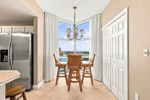 A kitchen with a stainless steel refrigerator, a dining table with four chairs, and a chandelier. - Palacio 1406 (Pensacola)