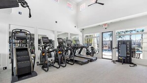 Ein Fitnessraum mit Laufbändern, Crosstrainern und einer Gewichtbank.